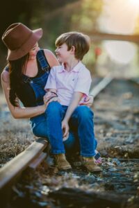 Happy mother and son sitting together on a railway enjoying a sunny day.