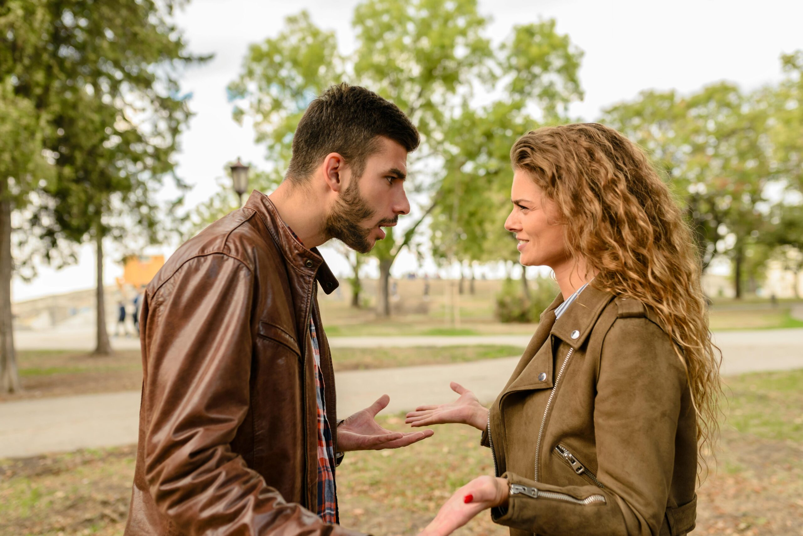 A couple having an argument outdoors, expressing frustration and conflict.